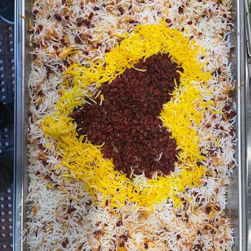 A large tray of Persian rice with a heart-shaped design of barberries and saffron rice.
